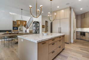 Expansive kitchen island with a marble countertop and white oak cabinetry