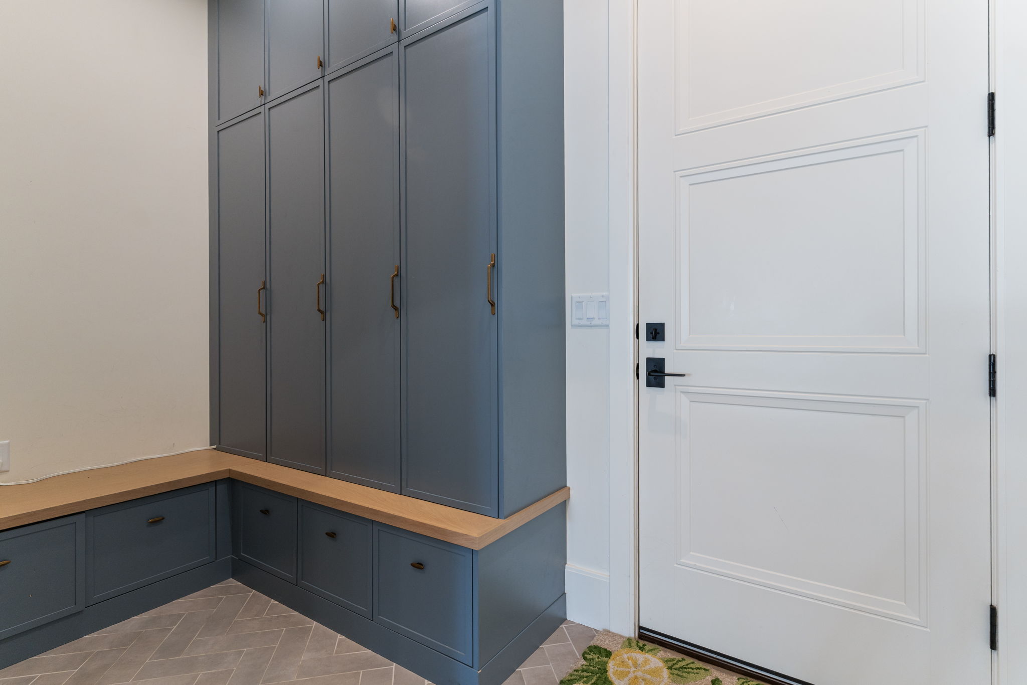 Custom cabinetry featuring floor-to-ceiling storage and lower drawers, complemented by a light wood-finish benchtop