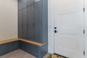 Custom cabinetry featuring floor-to-ceiling storage and lower drawers, complemented by a light wood-finish benchtop