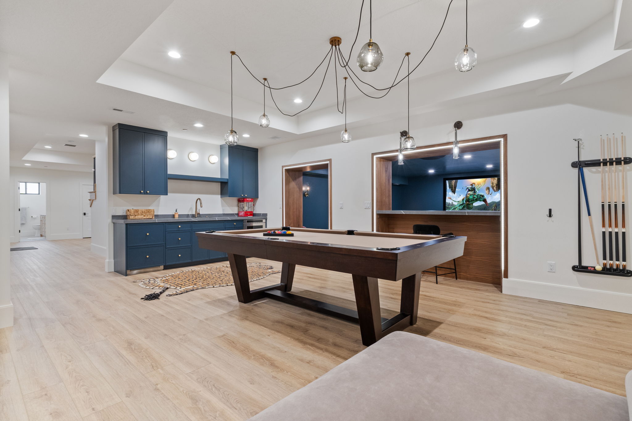 Recreation room featuring wood-finish flooring, a wet bar with blue cabinetry, a built-in media niche, and recessed lighting