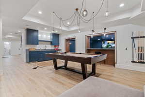 Recreation room featuring wood-finish flooring, a wet bar with blue cabinetry, a built-in media niche, and recessed lighting