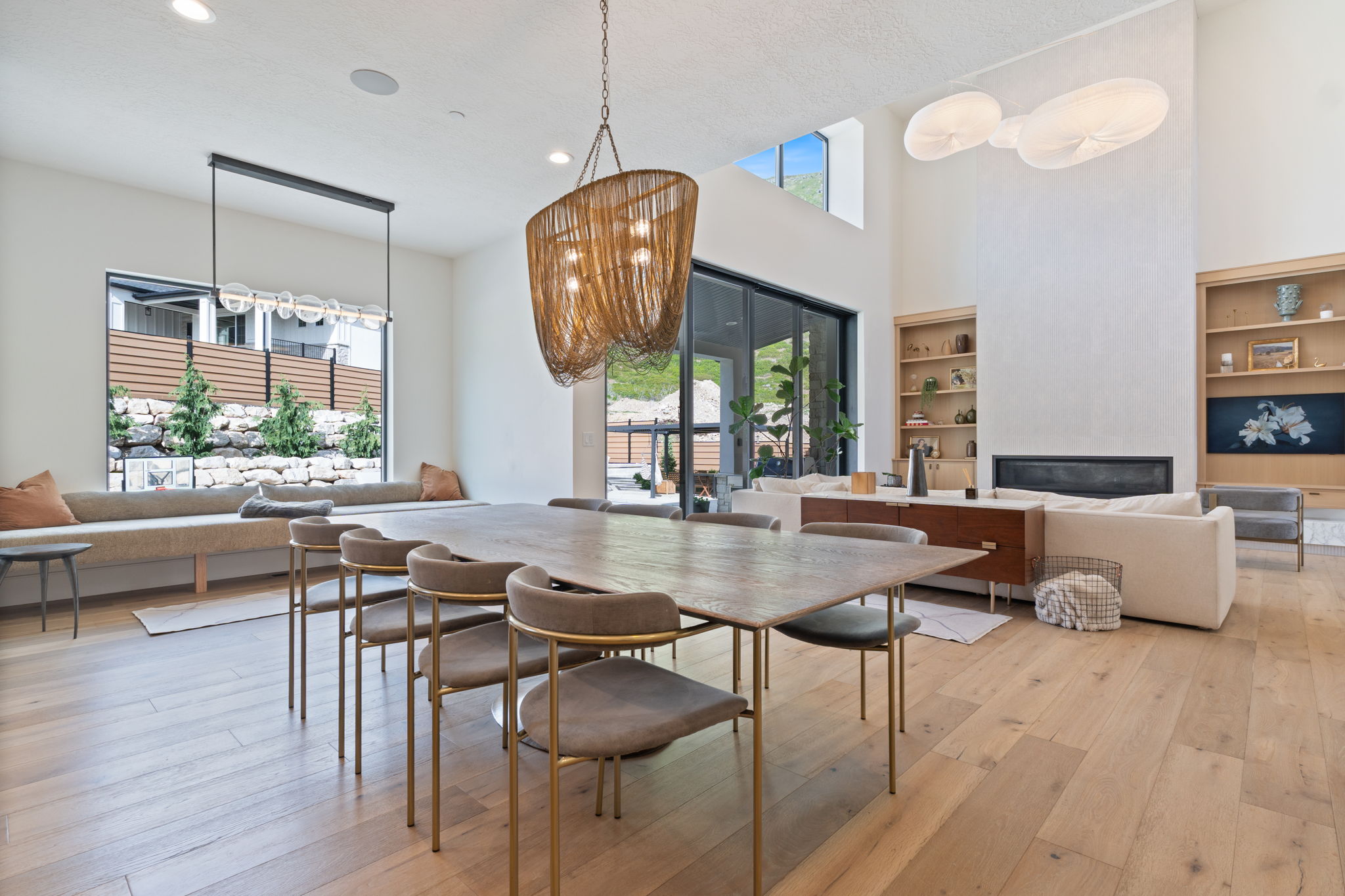 Spacious open-concept living area featuring light wood-finish flooring, a contemporary fireplace, and a high vaulted ceiling