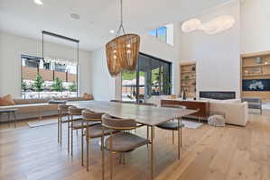 Spacious open-concept living area featuring light wood-finish flooring, a contemporary fireplace, and a high vaulted ceiling