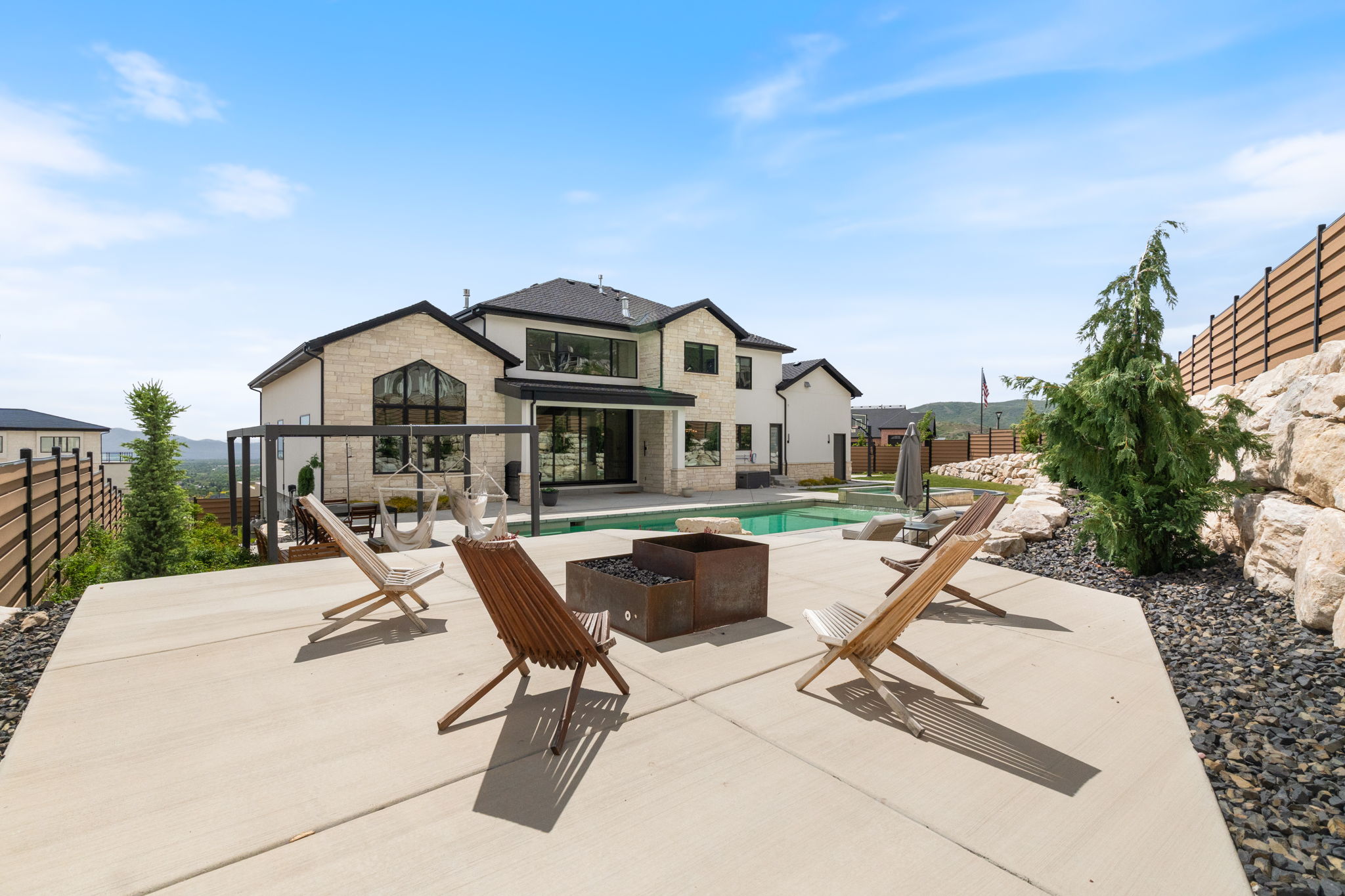 Expansive concrete patio with a fire pit, overlooking a swimming pool