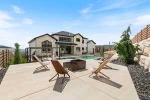 Expansive concrete patio with a fire pit, overlooking a swimming pool