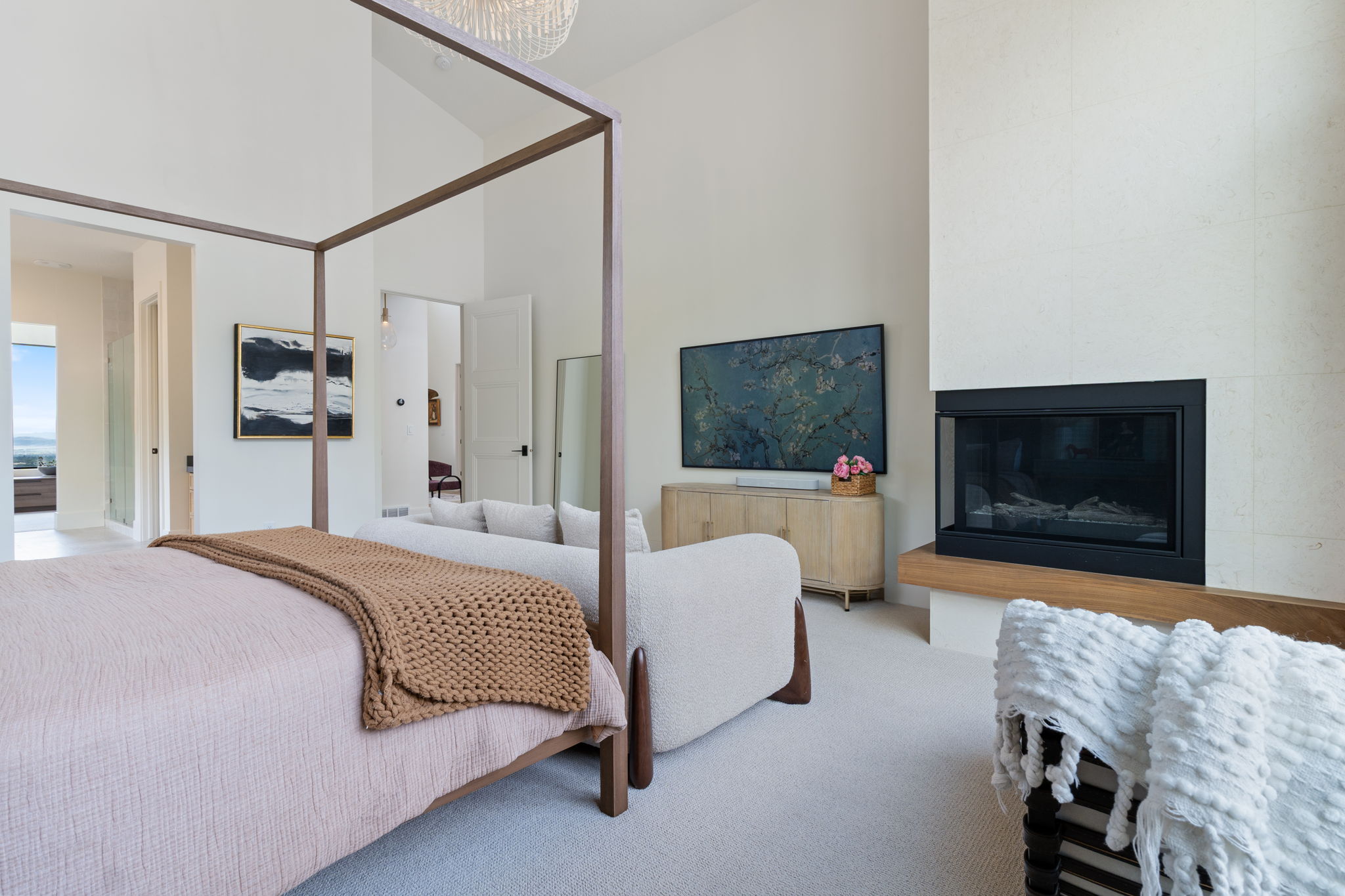 Vaulted ceilings enhance this space featuring a modern fireplace with a wood mantle, an integrated television, and light-toned carpeting