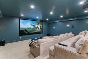 Dedicated media room featuring a large projection screen, recessed lighting, and wall-mounted sconces