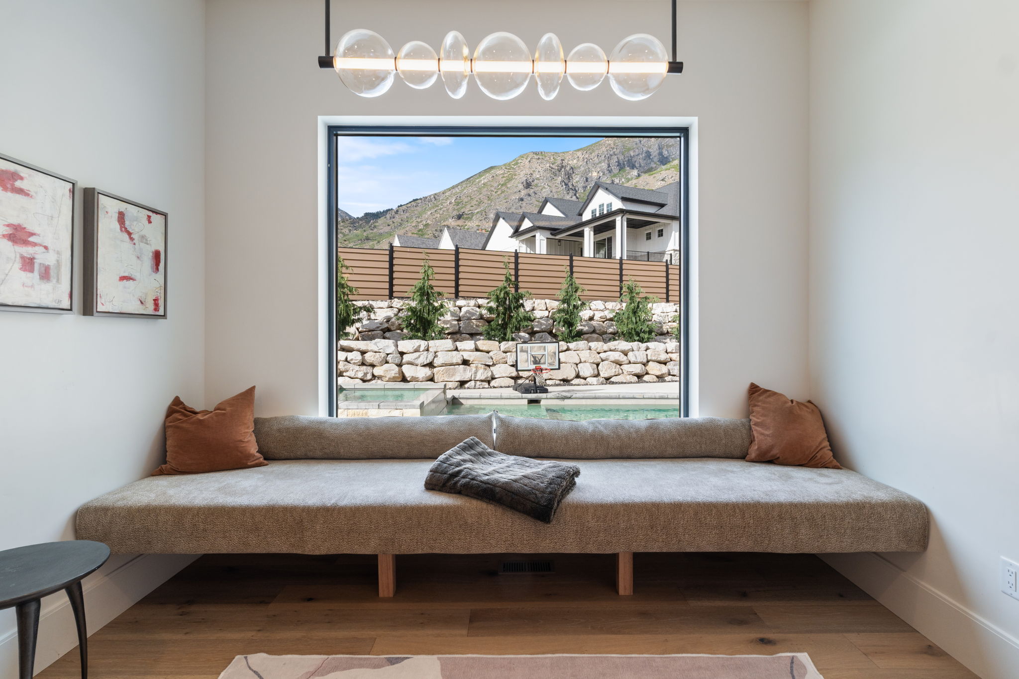 Built-in window bench with a modern linear chandelier and wood-finish flooring