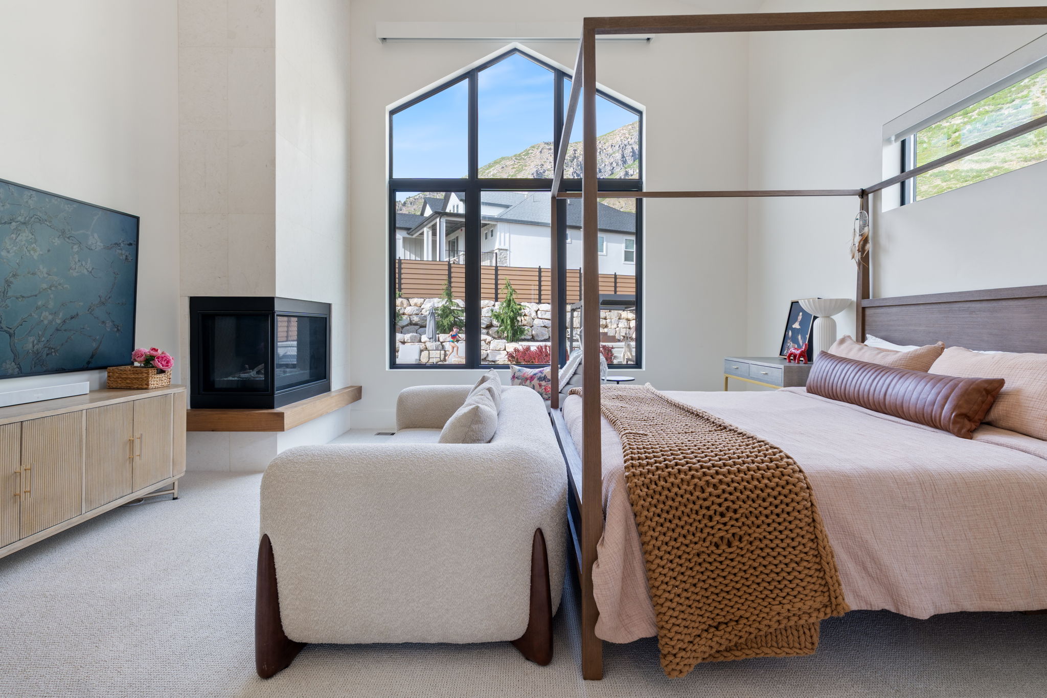 Corner fireplace with a wood mantle, high vaulted ceilings, and large architectural windows
