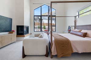 Corner fireplace with a wood mantle, high vaulted ceilings, and large architectural windows