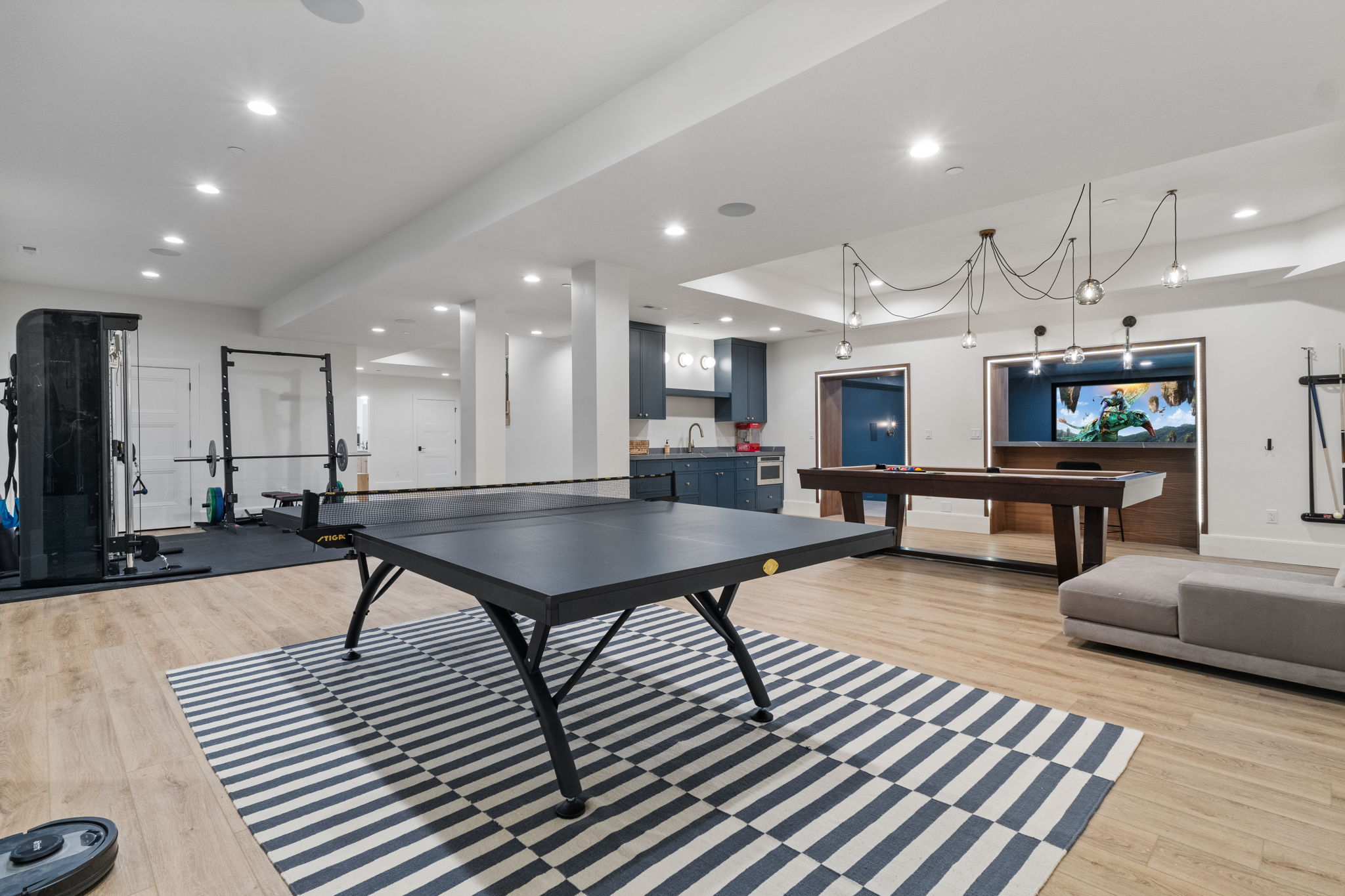 Spacious entertainment room featuring wood-finish flooring, recessed lighting, and a modern light fixture