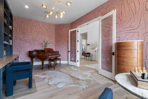 Elegant room featuring light wood-finish flooring and a distinctive patterned wallpaper