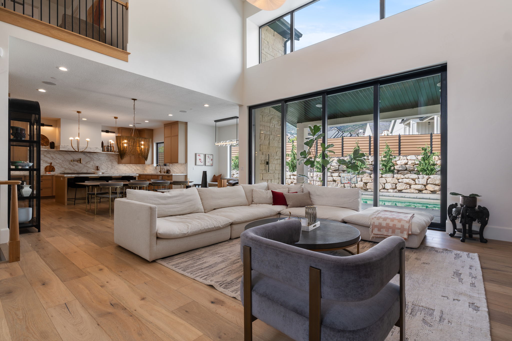 Spacious living area featuring high ceilings, wood-finish flooring, and expansive floor-to-ceiling windows