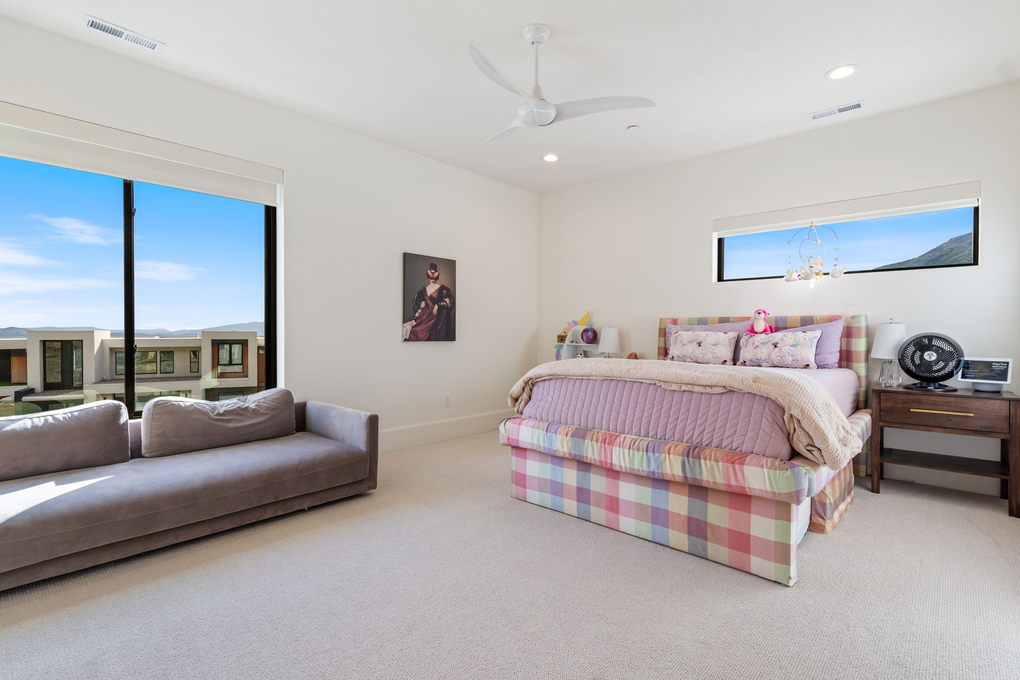Spacious room featuring broad windows with distant structures and mountain scenery, recessed lighting, and a ceiling fan