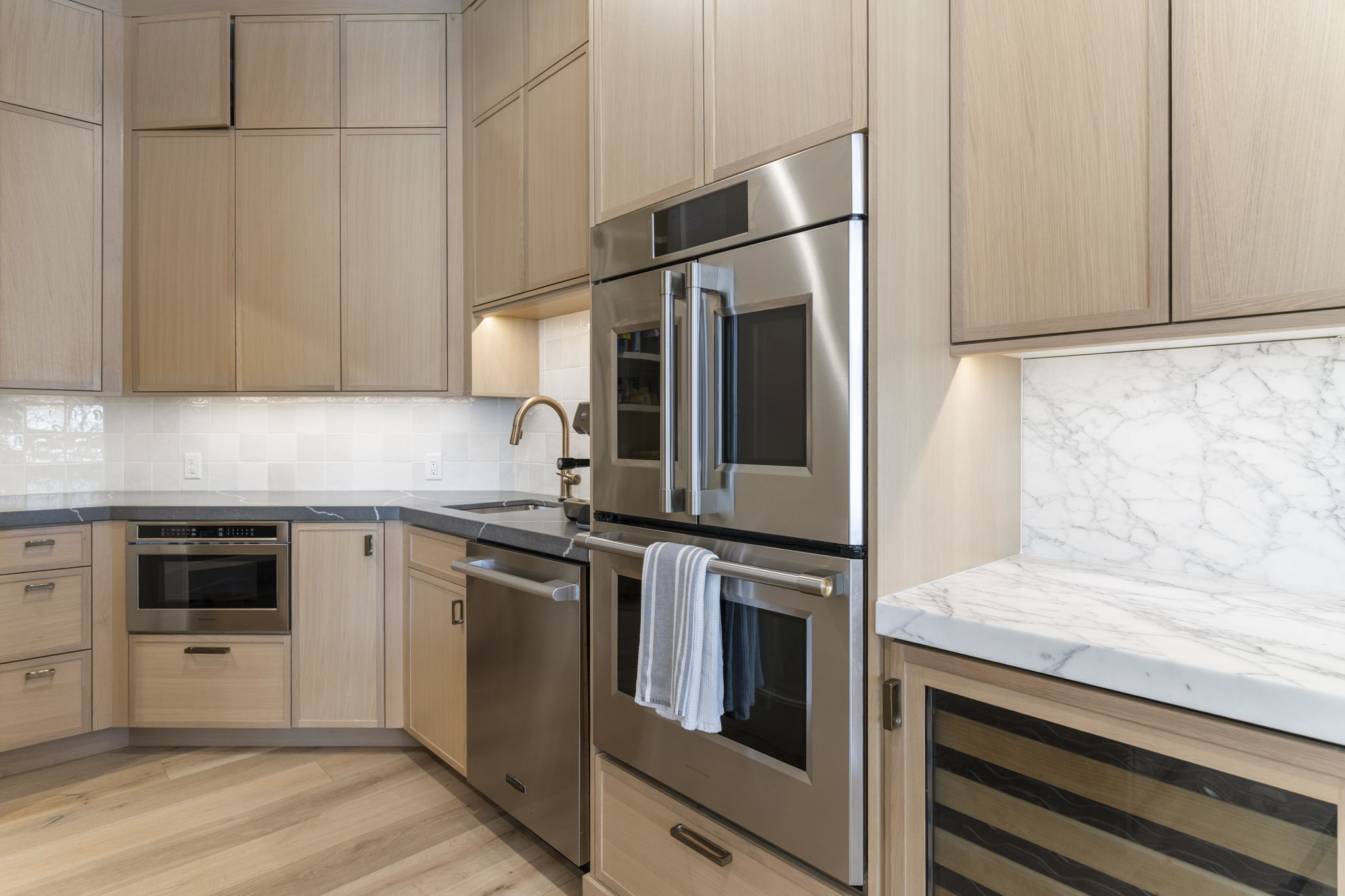 White oak cabinetry with brass hardware, Monogram stainless steel double oven, and under-cabinet lighting
