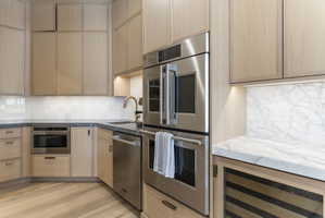 White oak cabinetry with brass hardware, Monogram stainless steel double oven, and under-cabinet lighting