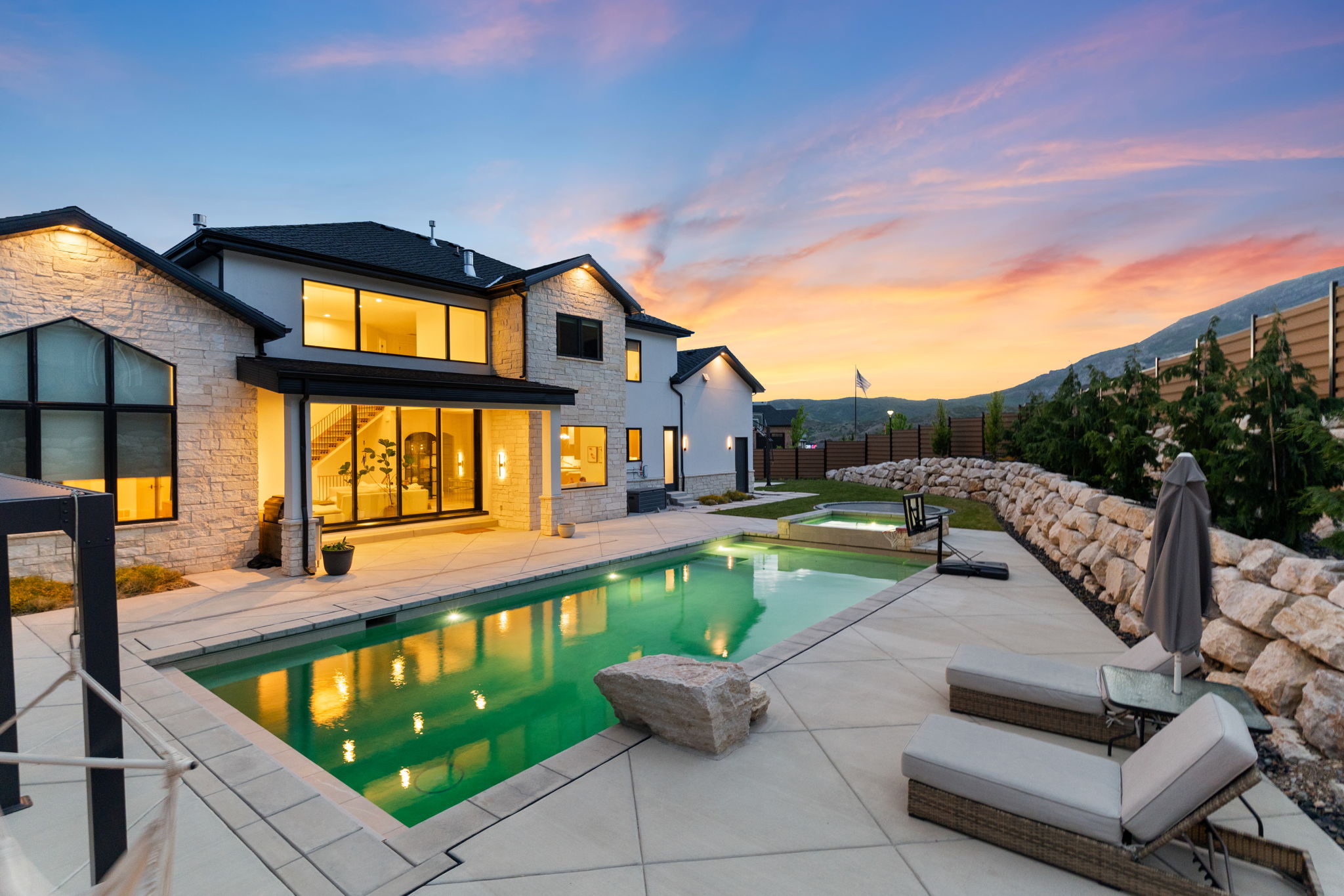 Expansive rear exterior featuring a swimming pool, integrated spa, and spacious concrete patio