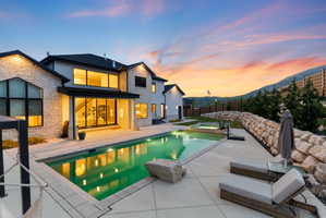 Expansive rear exterior featuring a swimming pool, integrated spa, and spacious concrete patio