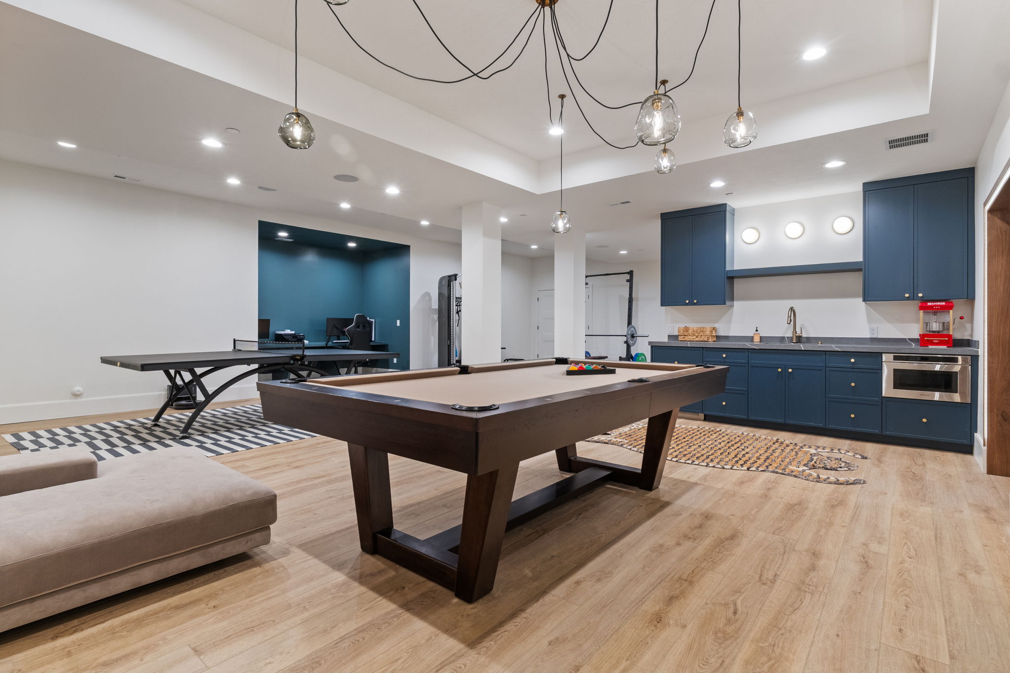 Spacious recreational area featuring wood-finish flooring, recessed lighting, and a modern chandelier