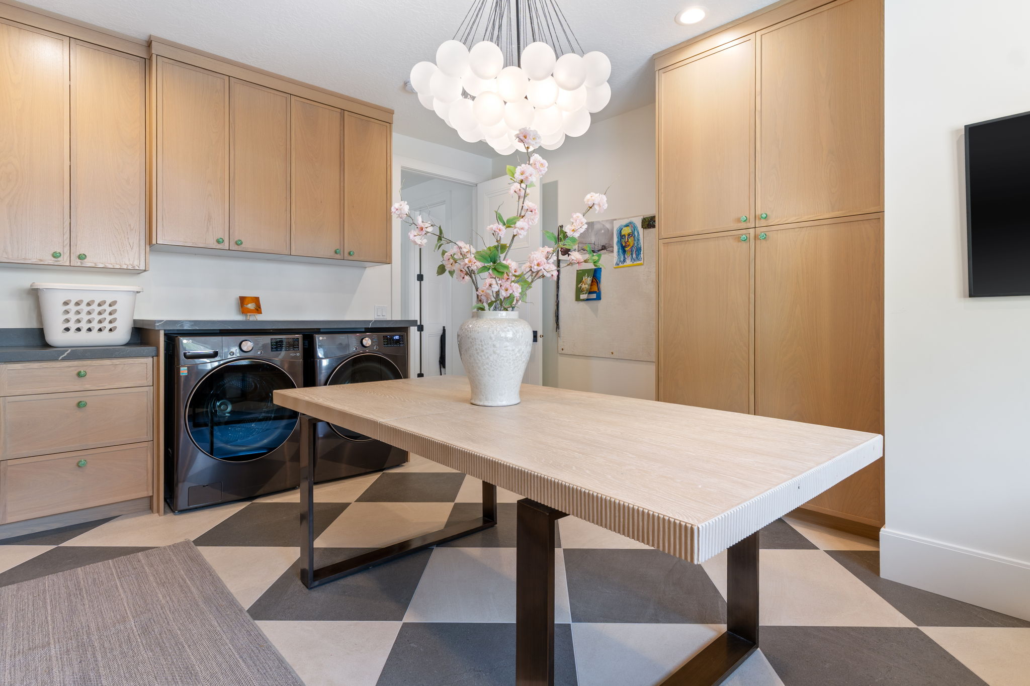 Utility room featuring extensive built-in cabinetry, dark stone countertops, and a modern spherical chandelier