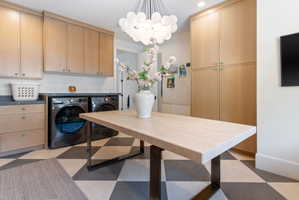 Utility room featuring extensive built-in cabinetry, dark stone countertops, and a modern spherical chandelier