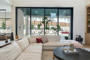 Spacious living area featuring large-format sliding glass doors, a stone accent wall, high ceilings, and built-in shelving