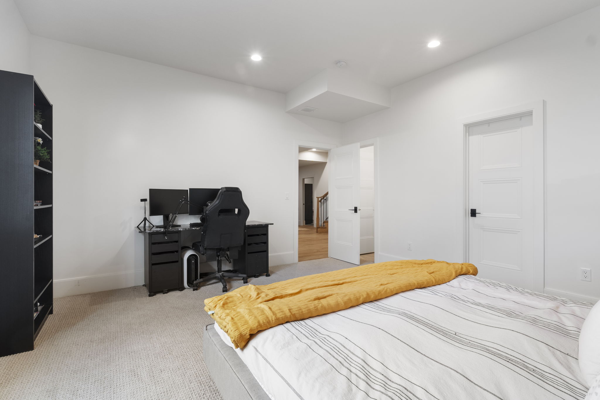 Bright bedroom featuring recessed lighting, a neutral carpet, white walls, and a white panel door with matte black hardware