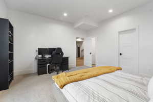 Bright bedroom featuring recessed lighting, a neutral carpet, white walls, and a white panel door with matte black hardware