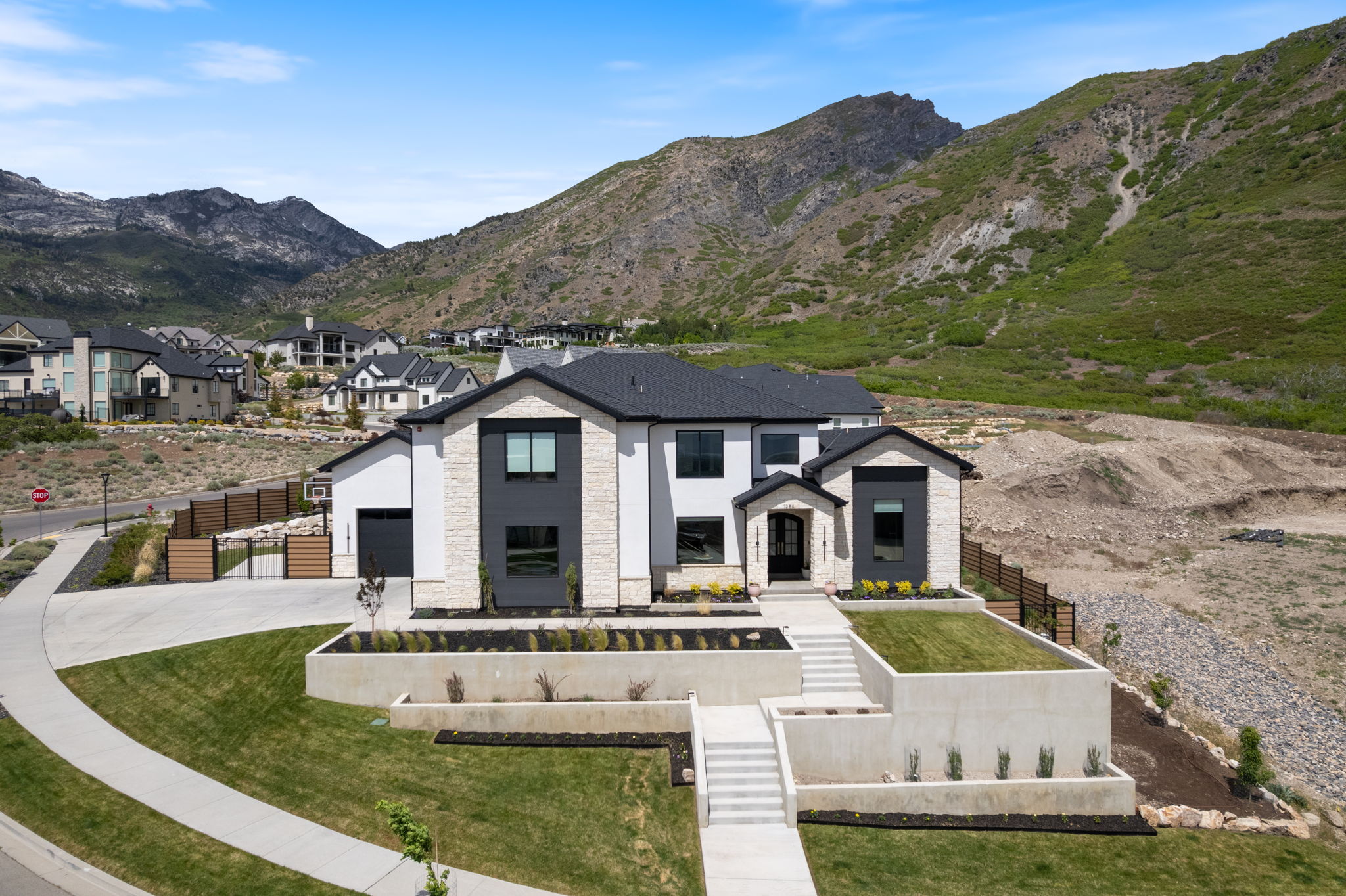 Modern dwelling featuring a dark roof, white stucco, and natural stone accents