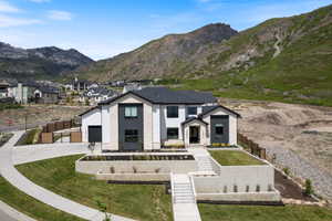 Modern dwelling featuring a dark roof, white stucco, and natural stone accents