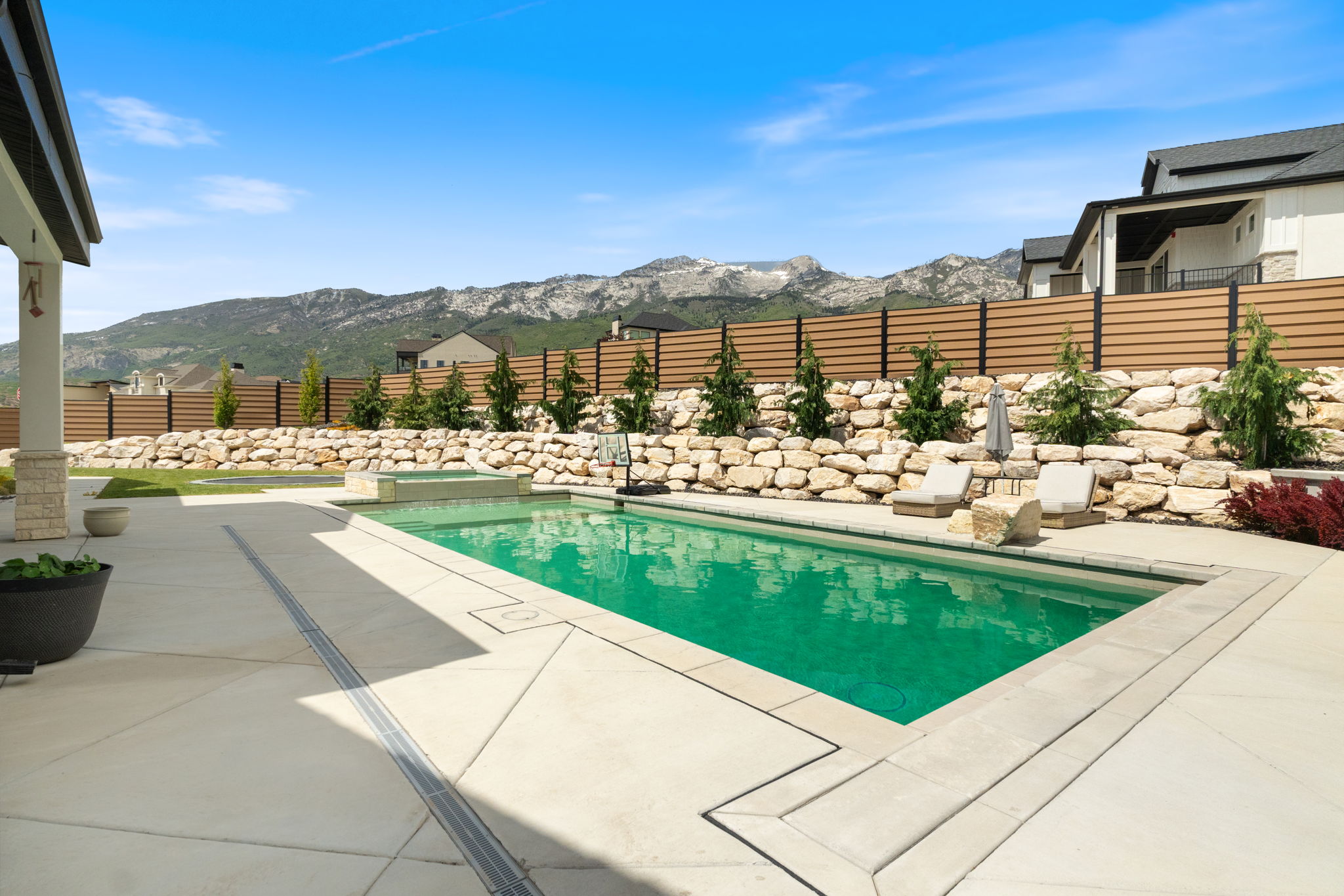 Expansive concrete patio featuring a rectangular swimming pool with integrated spa