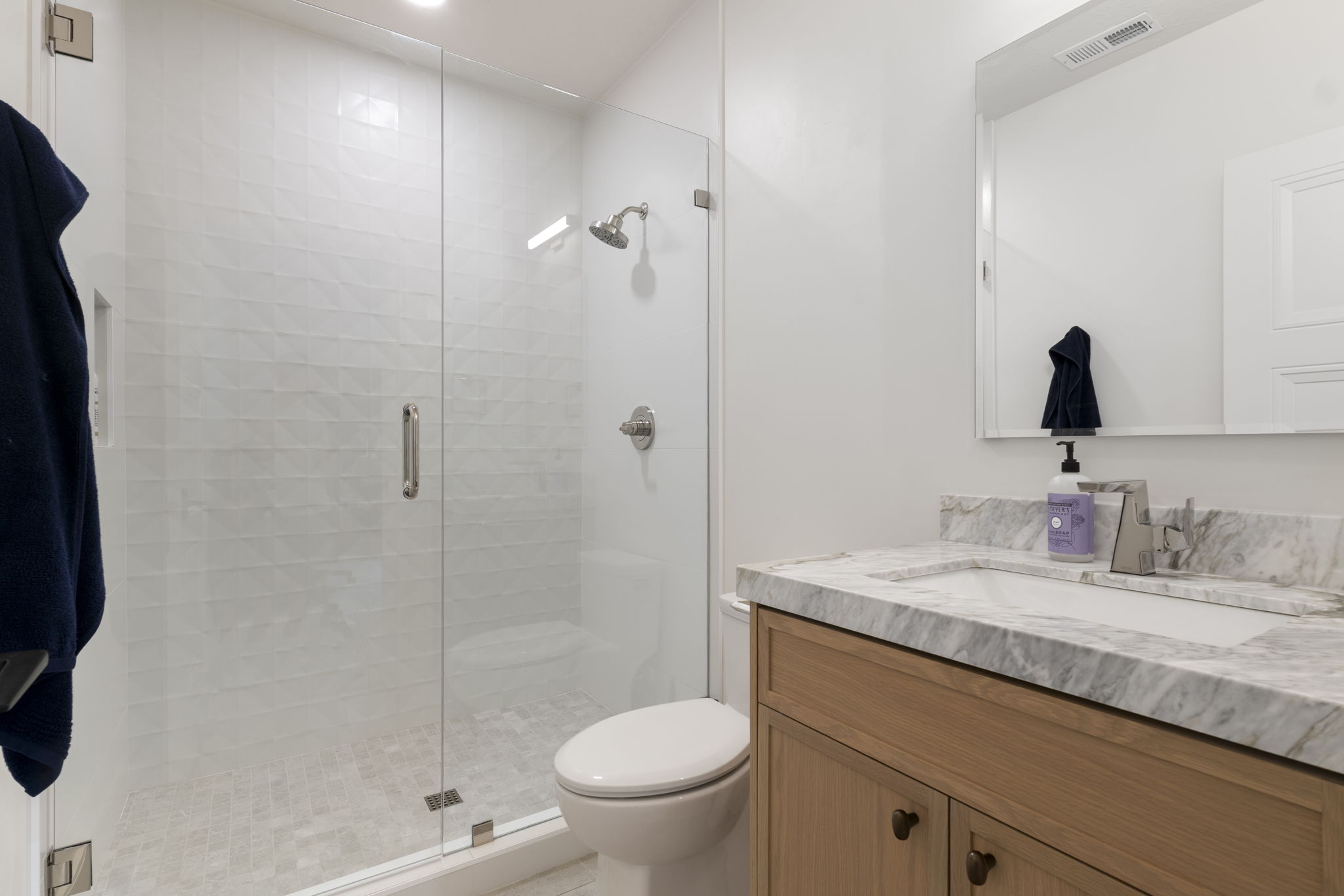 Walk-in shower with clear glass enclosure and tiled walls