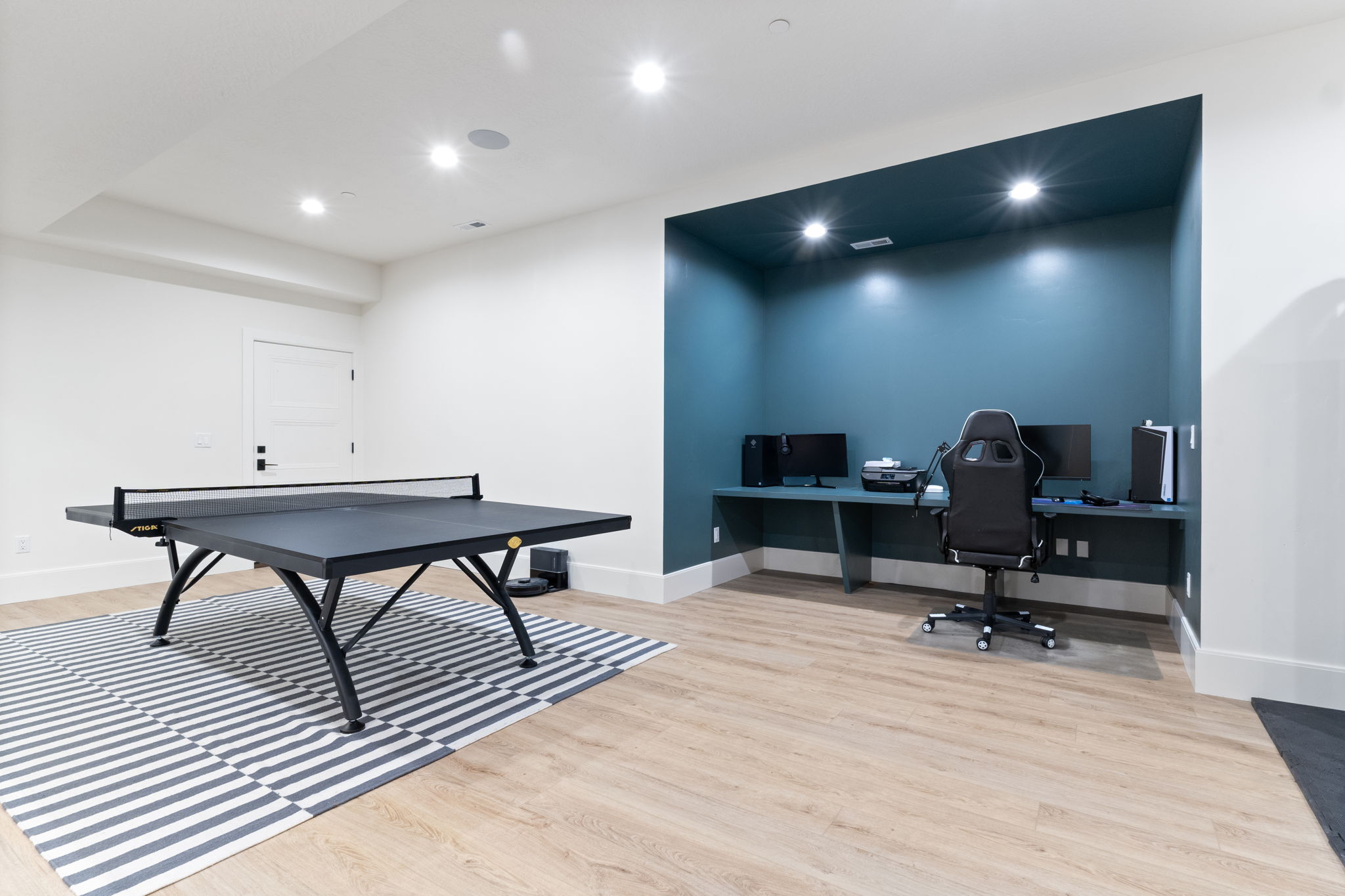 Finished lower level featuring light wood-finish flooring, recessed lighting, and a built-in desk area with accent wall