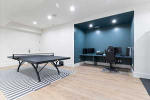 Finished lower level featuring light wood-finish flooring, recessed lighting, and a built-in desk area with accent wall