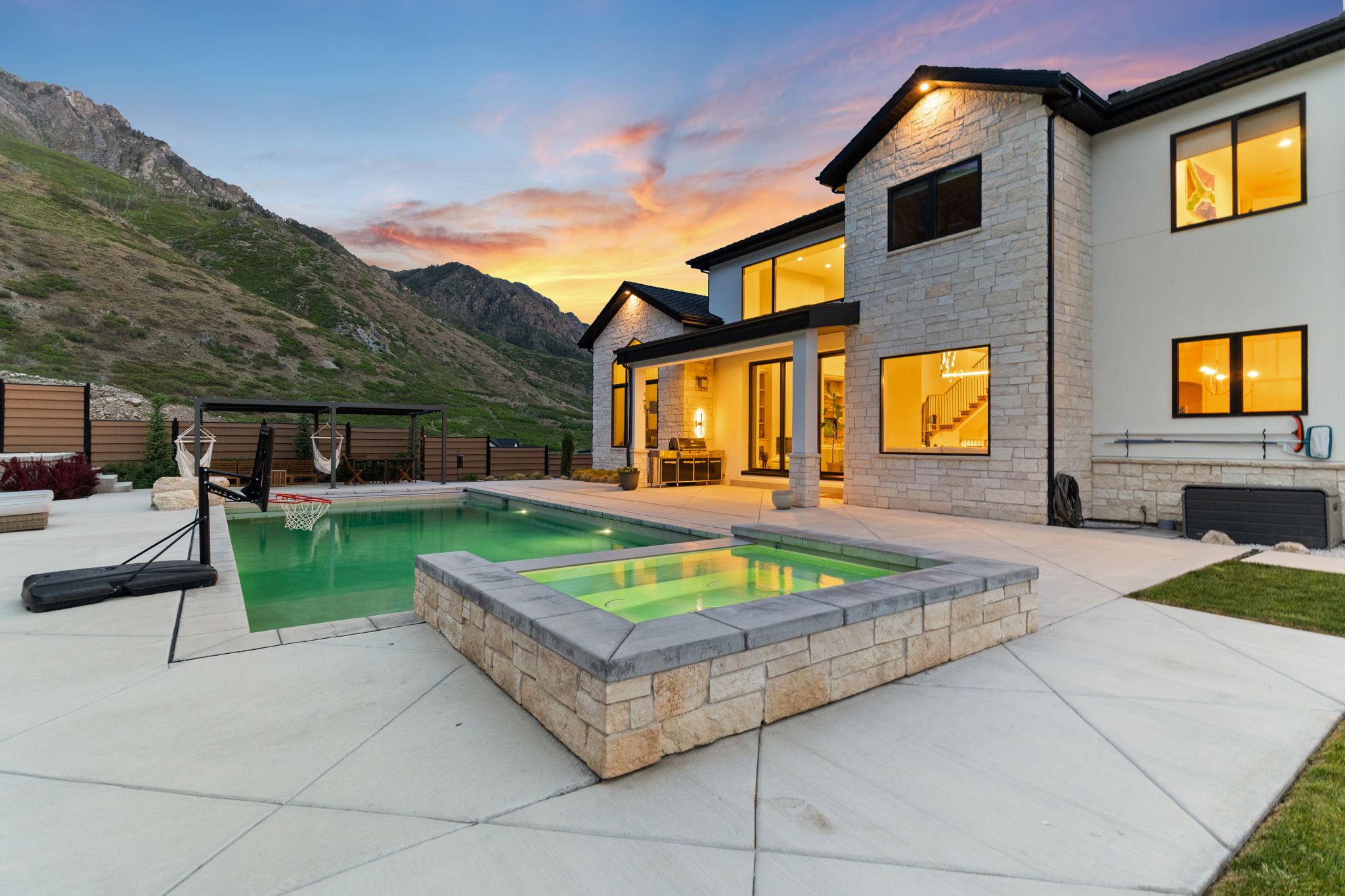 Expansive concrete patio featuring a swimming pool, integrated spa, and mountain backdrop