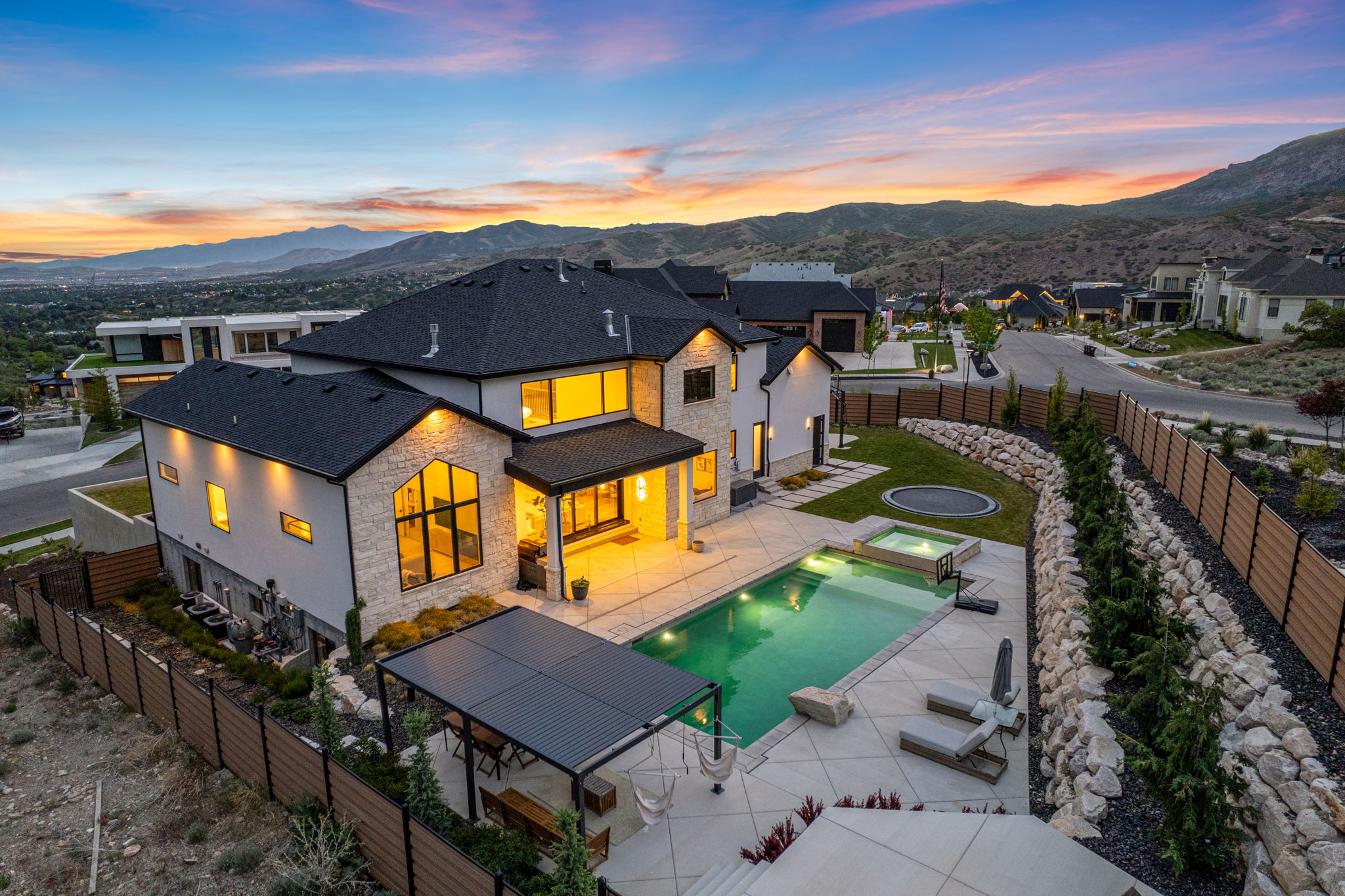 Modern home with stone and stucco facade, featuring an integrated swimming pool and hot tub