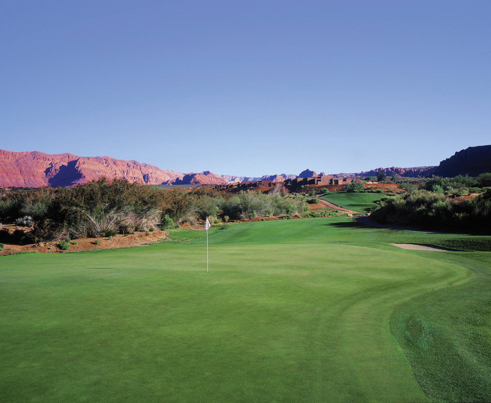 Lush green golf course with a prominent putting green and white flag