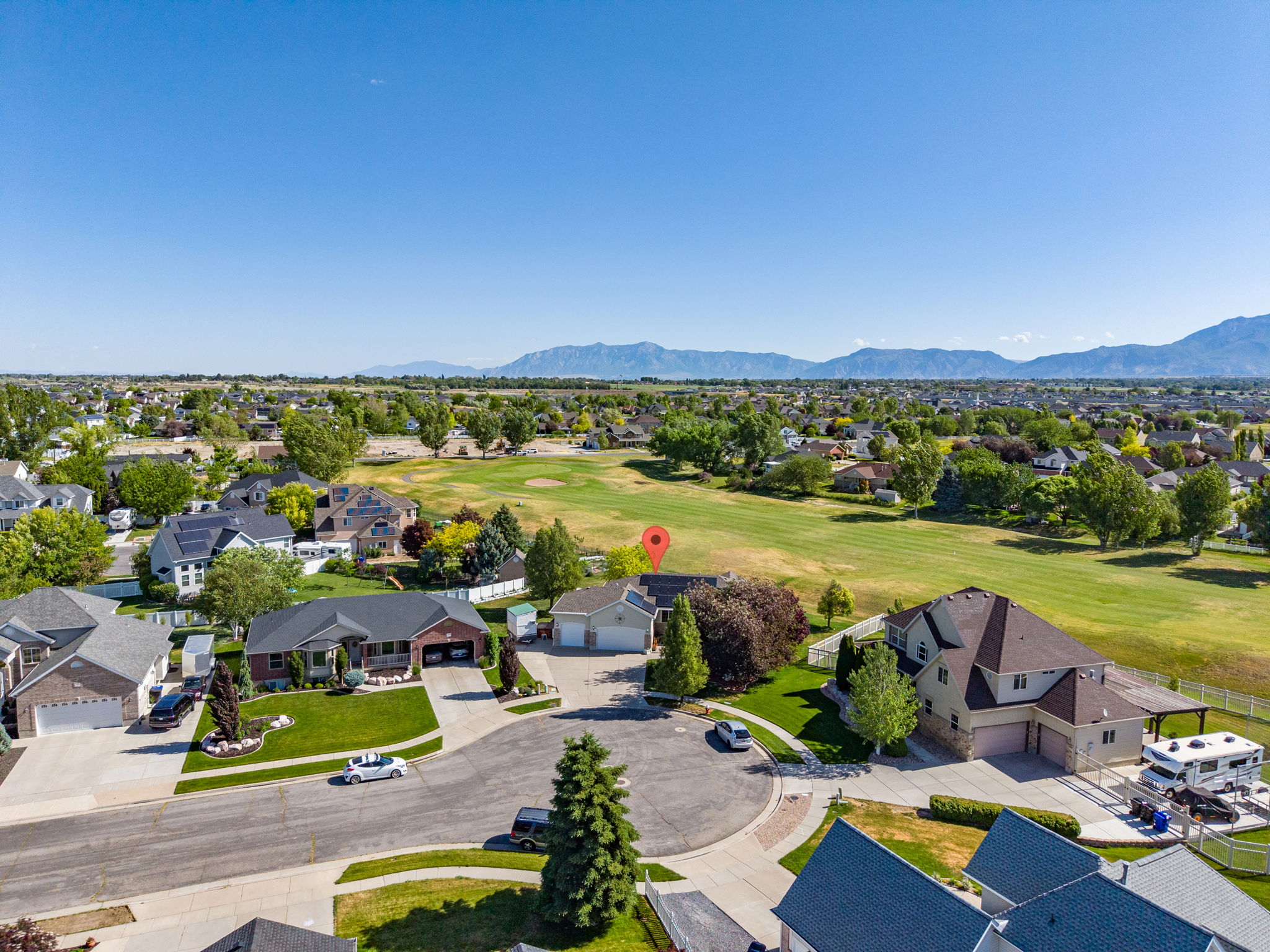 Spacious property featuring a large green lawn, mature trees, and a mountain backdrop