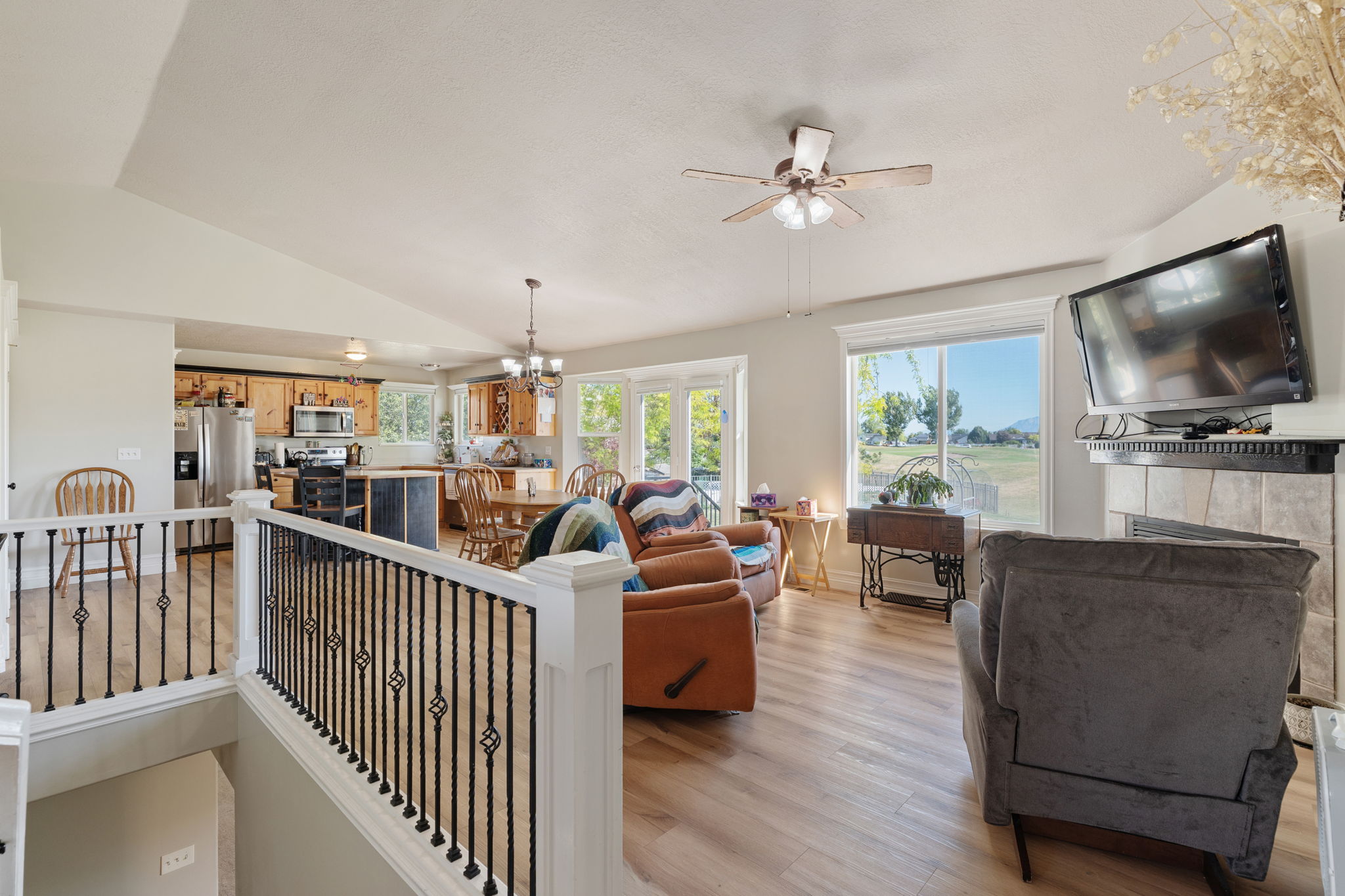 Living space featuring wood-finish flooring, a fireplace with a tile surround and mantel, and large windows