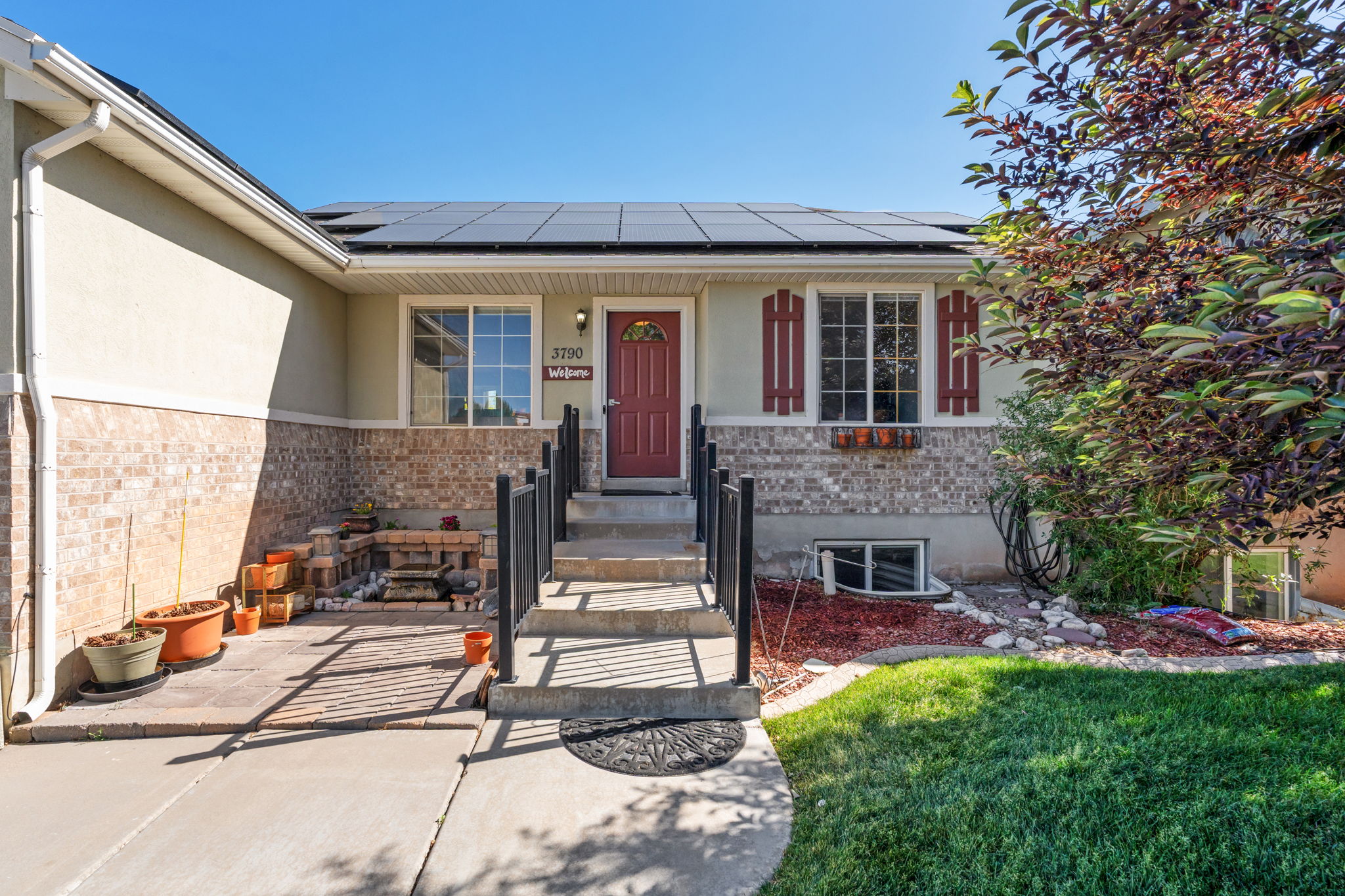 Front elevation with a red entry door and solar panels