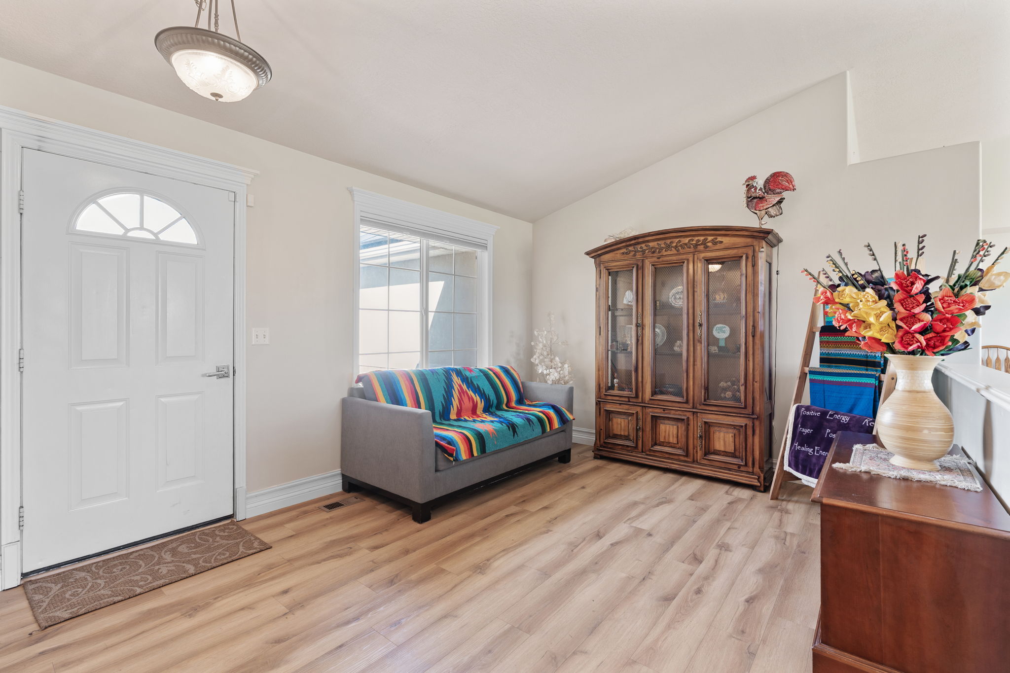 Entryway featuring wood-finish flooring, a white paneled door with an arched window, and a large window providing natural illumination