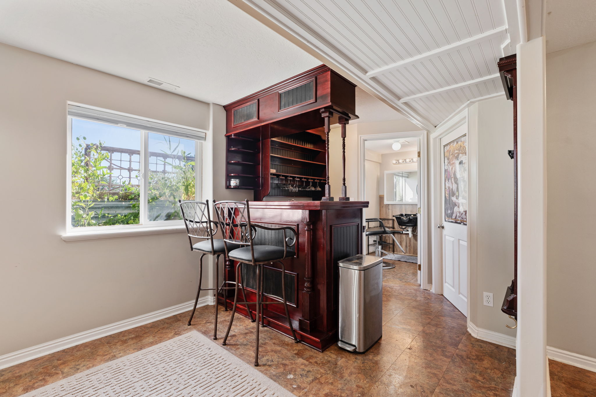 Built-in custom bar with rich wood finishes and overhead storage, complemented by warm-toned flooring and a paneled ceiling