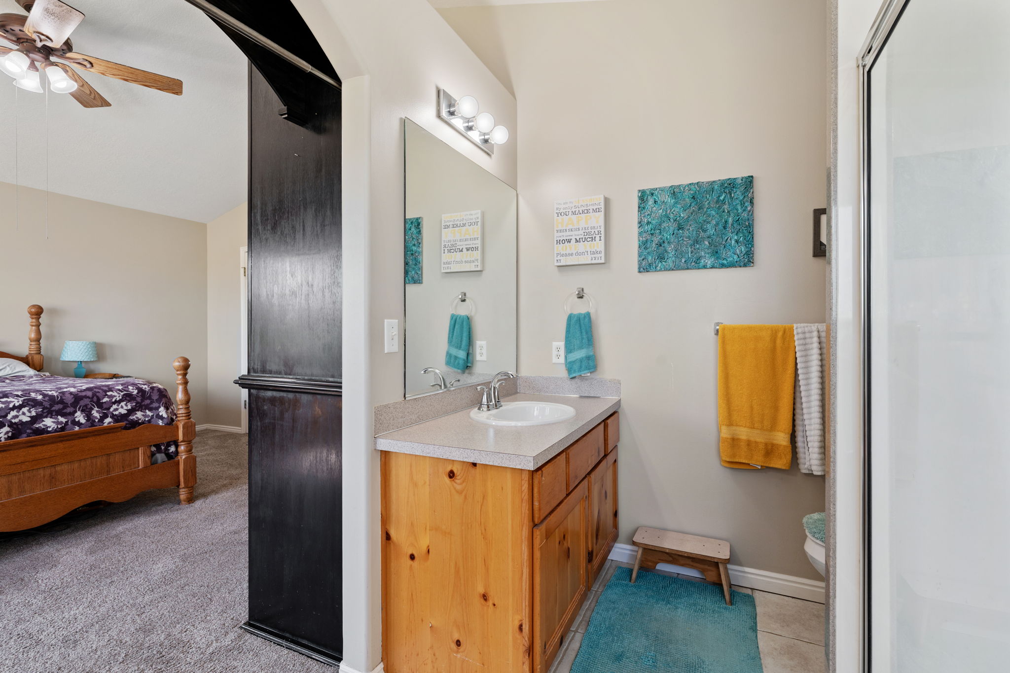 Vanity area featuring a light wood-finish cabinet with a light-toned countertop, an integrated sink, and an overhead vanity light fixture