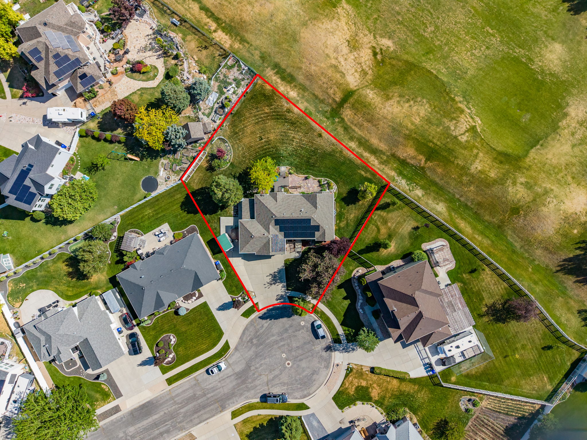 Expansive property with a cul-de-sac location, featuring a large residential structure, integrated solar panels, a substantial green yard, and mature landscaping