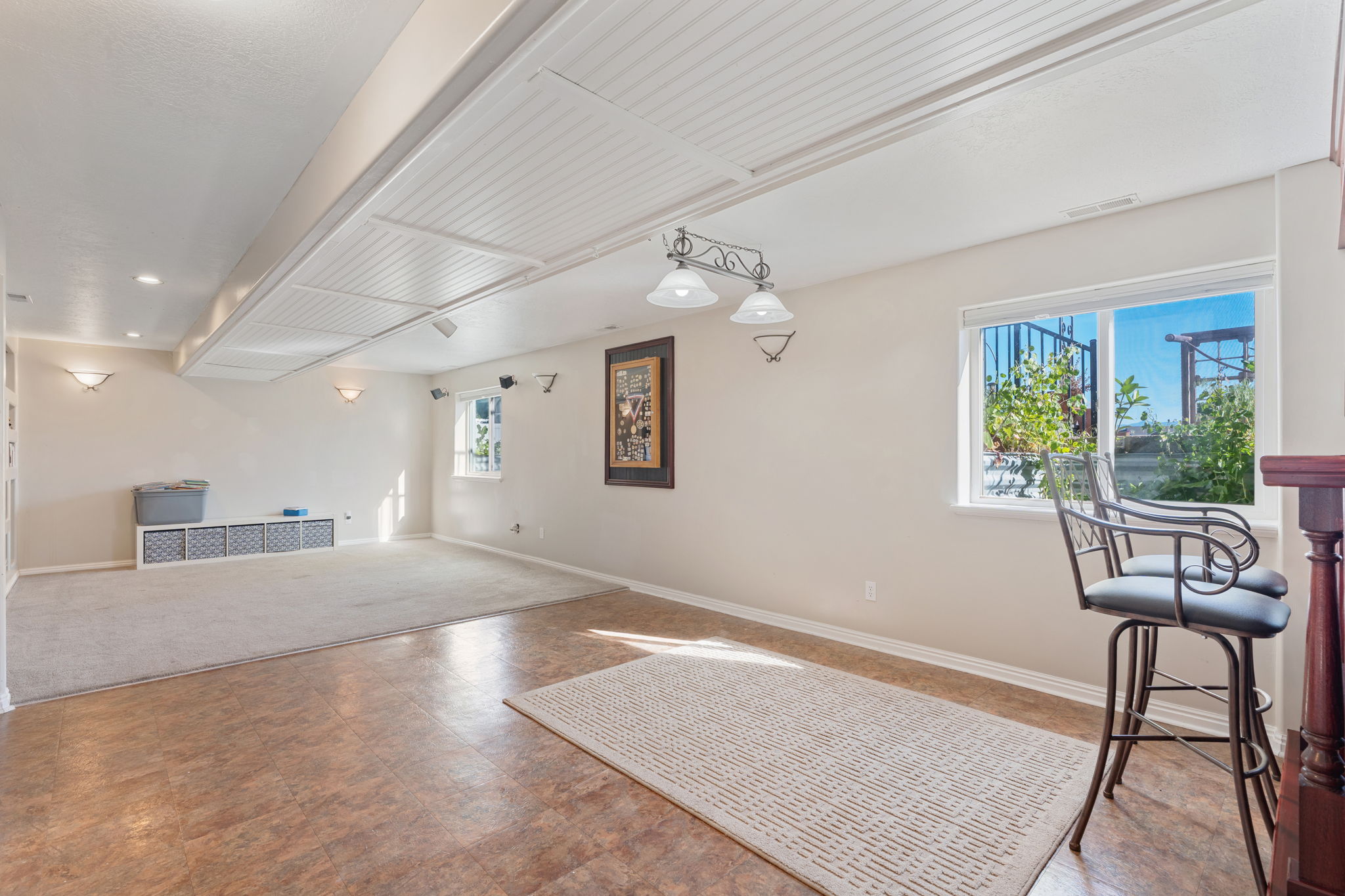 Spacious lower-level area featuring a blend of wood-finish flooring and carpeting, multiple windows, and recessed lighting
