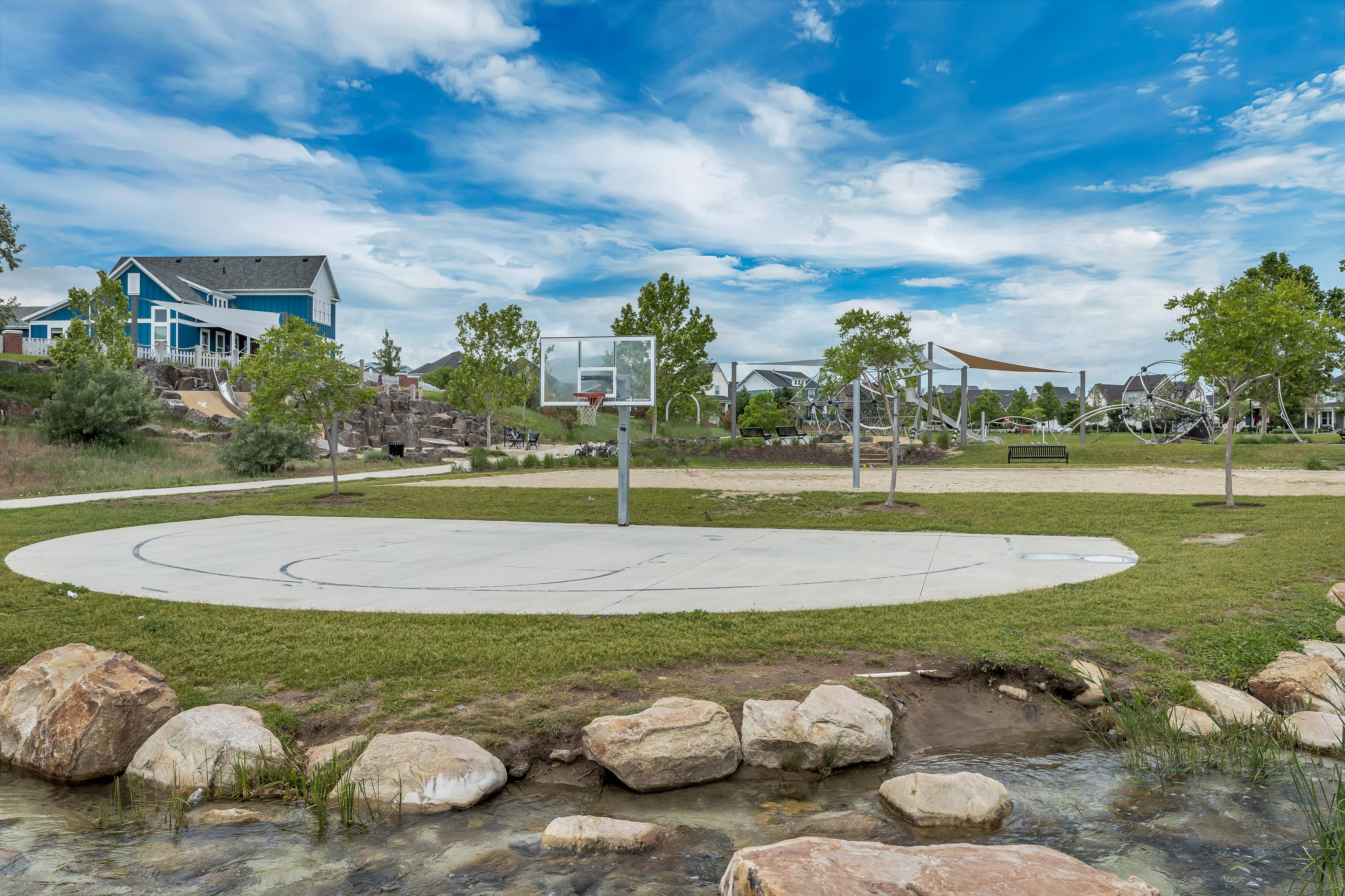 Concrete half-court basketball area surrounded by green lawn