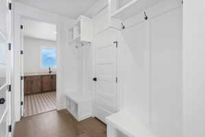 Entryway mudroom with built-in bench storage, integrated shelving, and coat hooks