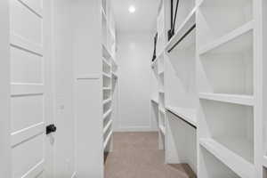 Walk-in closet featuring extensive built-in shelving, hanging rods, recessed lighting, and carpet flooring