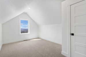 Attic room featuring a single-pane window with white trim, a recessed ceiling light, and a light-colored carpeted floor