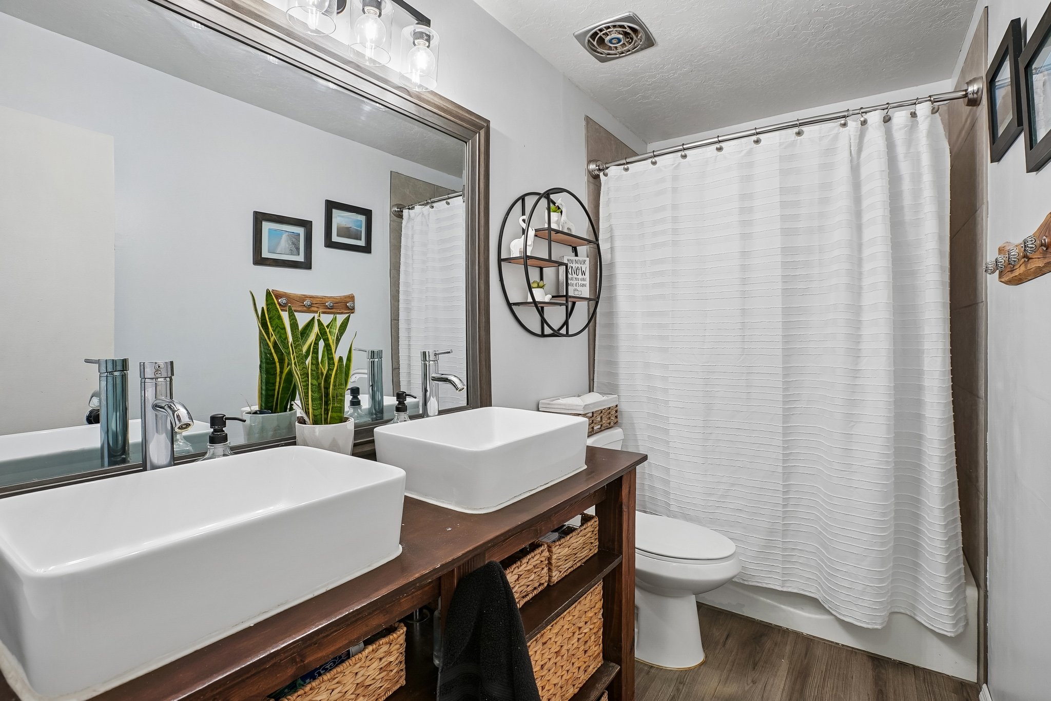 Dual vessel sinks atop a wood-finish vanity with integrated storage baskets